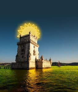 Europe, Portugal, Lisbon. The tower of Belem in Lisbon illuminated by the setting sun with a boat passing in the background.